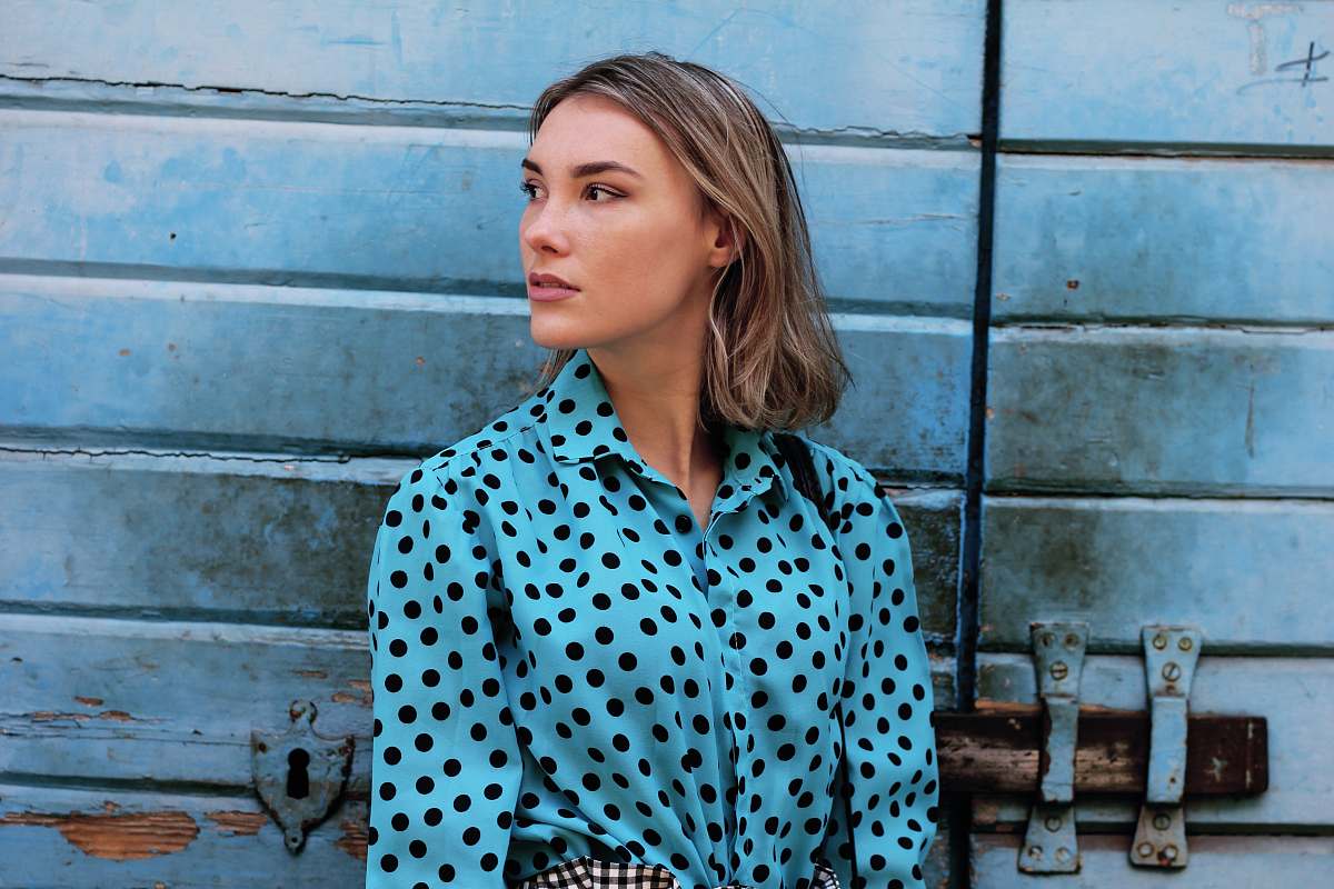 human shallow focus photo of teal and black polka-dot long-sleeved shirt person