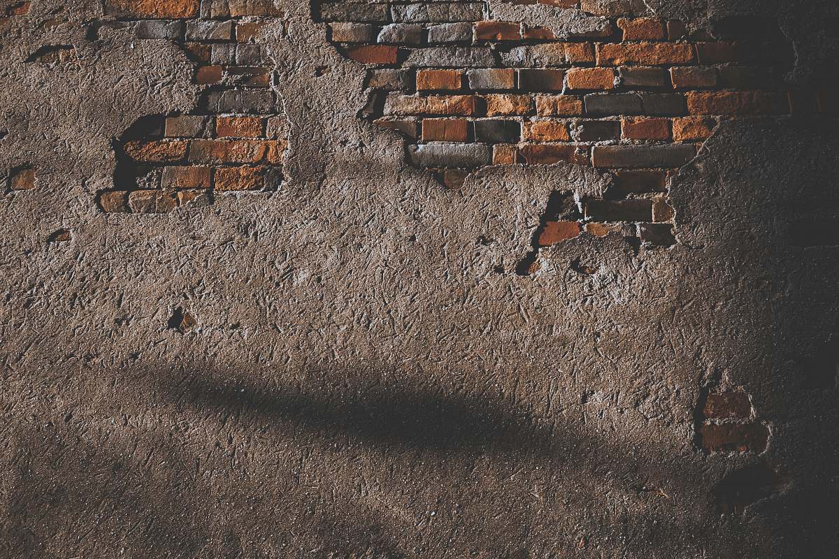 This captivating image features a distressed brick wall, showcasing broken bricks that narrate a story of time and resilience. A gentle shadow of a person gracefully stretches across its surface, adding depth and intrigue to the scene. Perfect for use in themes related to urban decay, architectural elements, loneliness, or artistic expression, this photograph can enhance design projects, blog posts, or marketing materials that seek to evoke a sense of nostalgia or solitude.