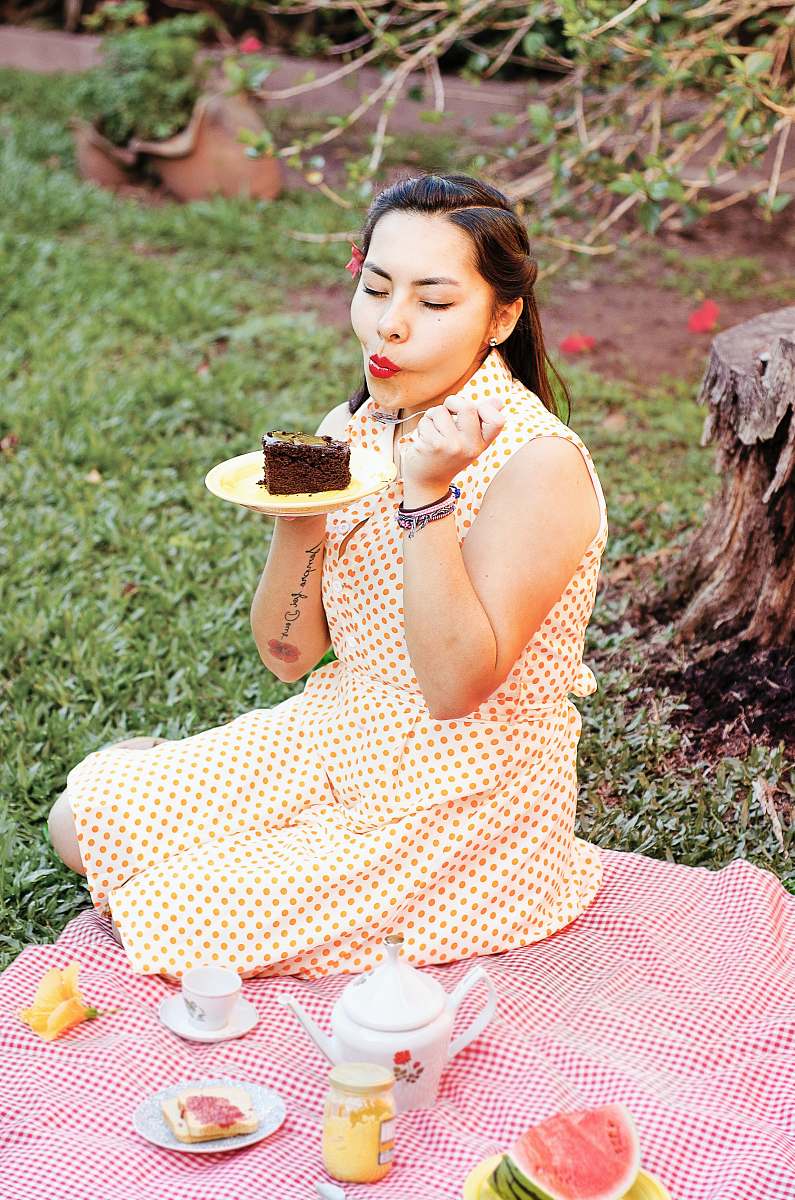 Capture the essence of leisure with this vibrant image of a joyful woman savoring a delicious slice of cake while seated on a lush green grass field. Surrounded by the warmth of a sunny day, she also enjoys refreshing watermelon, making this scene perfect for highlighting moments of joy, relaxation, and outdoor celebrations. Ideal for blogs, social media posts, and marketing campaigns focusing on picnics, desserts, or lifestyle content.