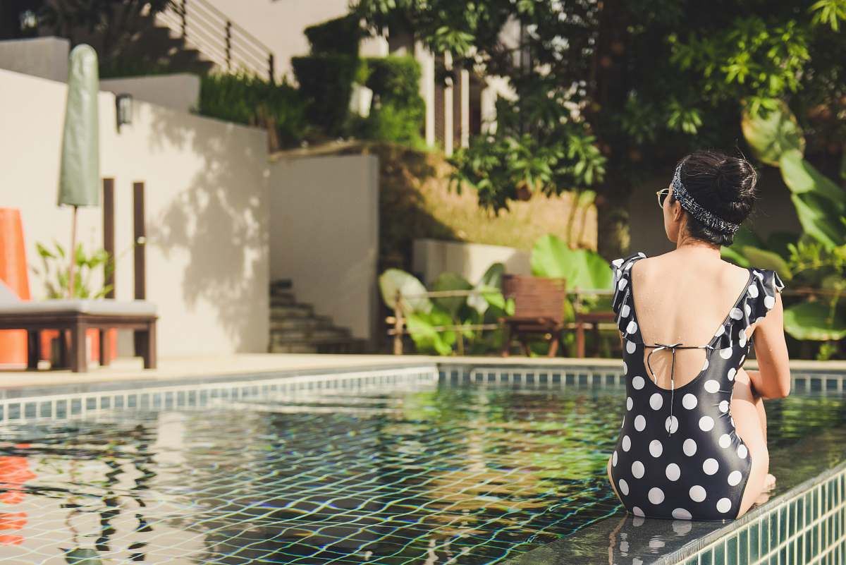 human woman sitting beside pool near house during daytime person