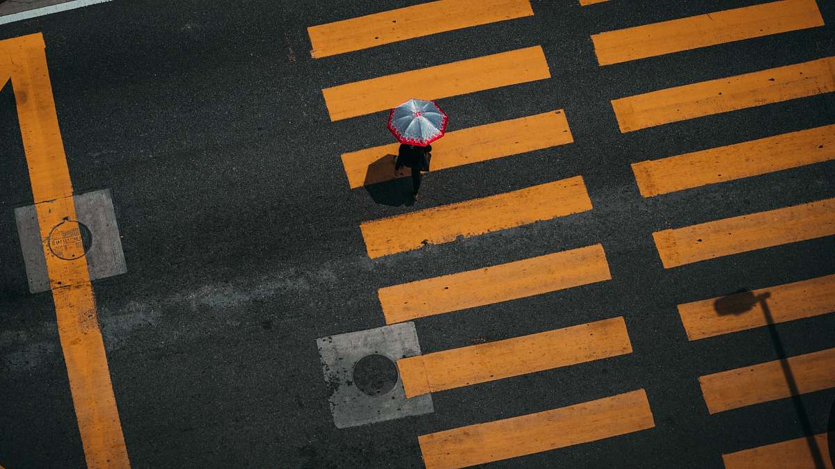 tarmac bird's-eye photography of person walking on pedestrian lane road