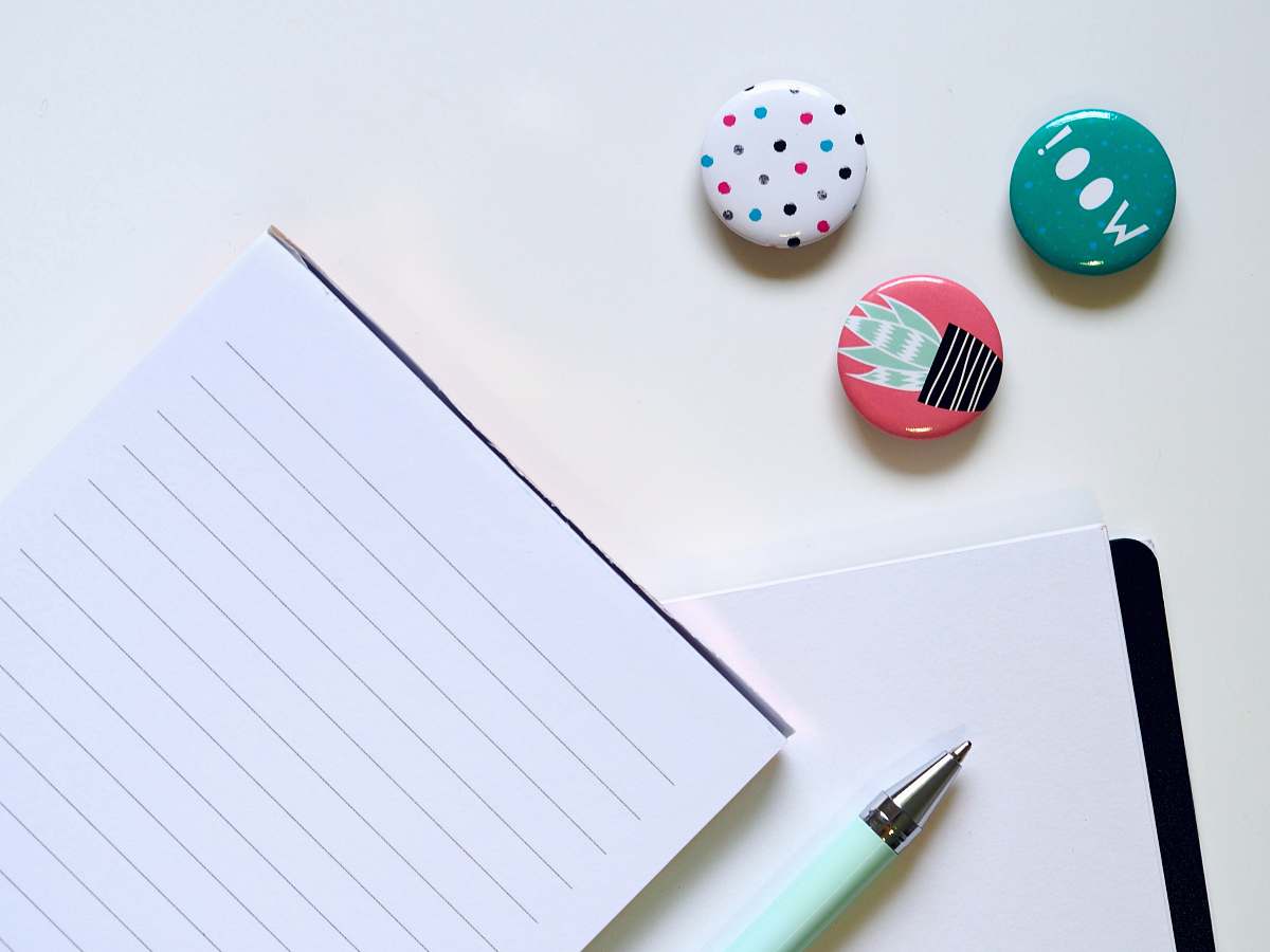 emblem pen beside ruled paper logo