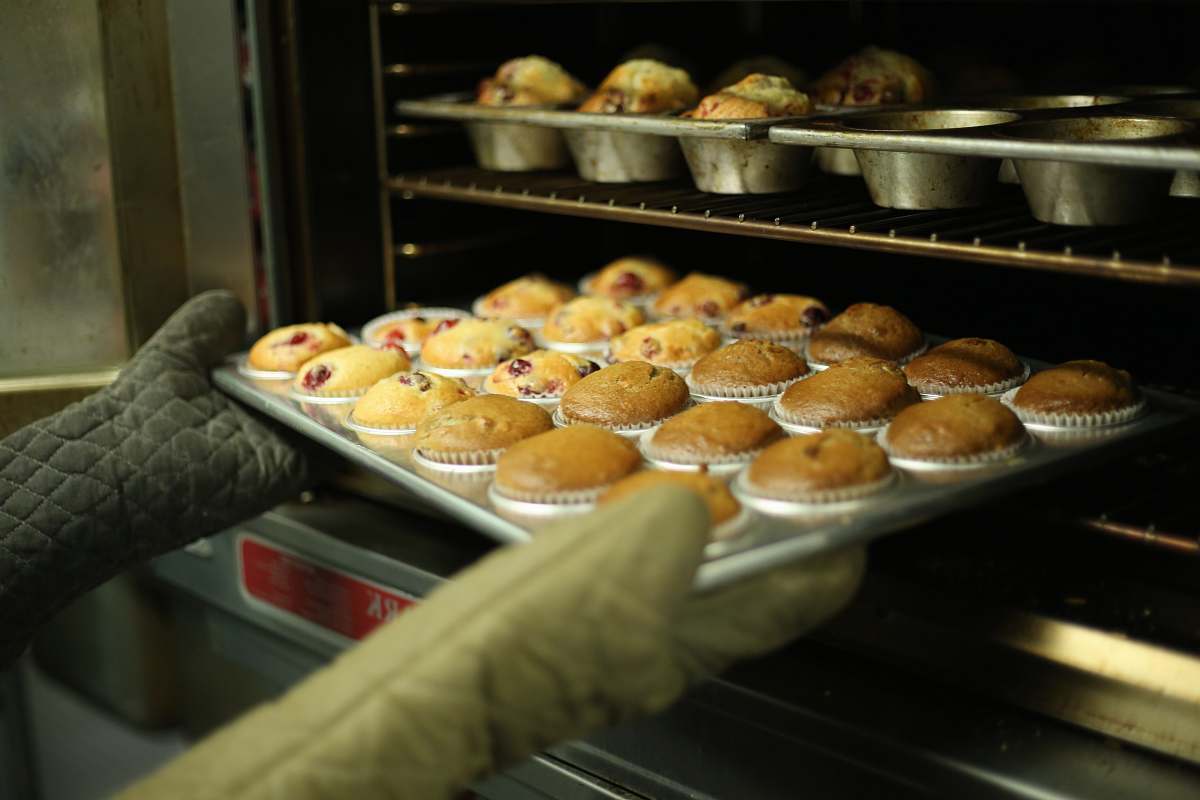food person holds tray of muffins on tray cupcakes
