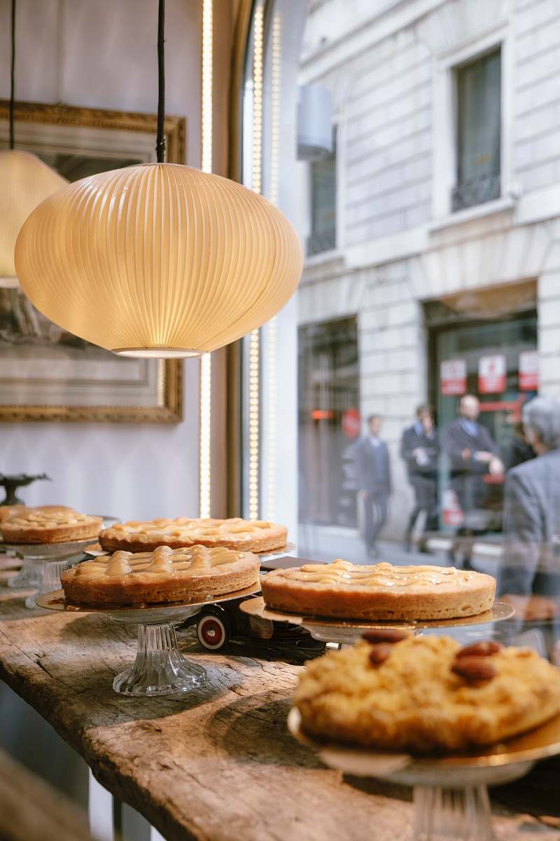 human round white pendant lamp above assorted cakes on display person