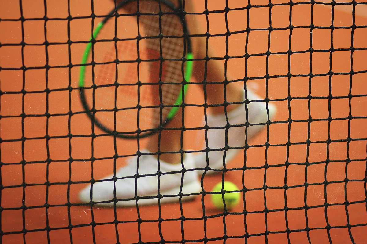 tennis person wearing pair of white low-top sneakers while holding Wilson tennis racket sweden
