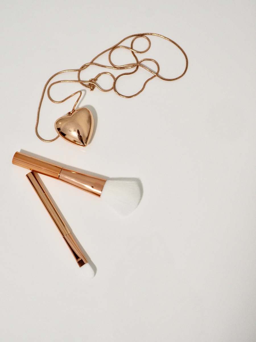 makeup gold heart pendant necklace and two gold handled makeup brushes gold