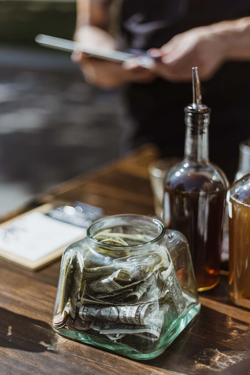 drink banknotes in clear glass container on wooden surface liquor