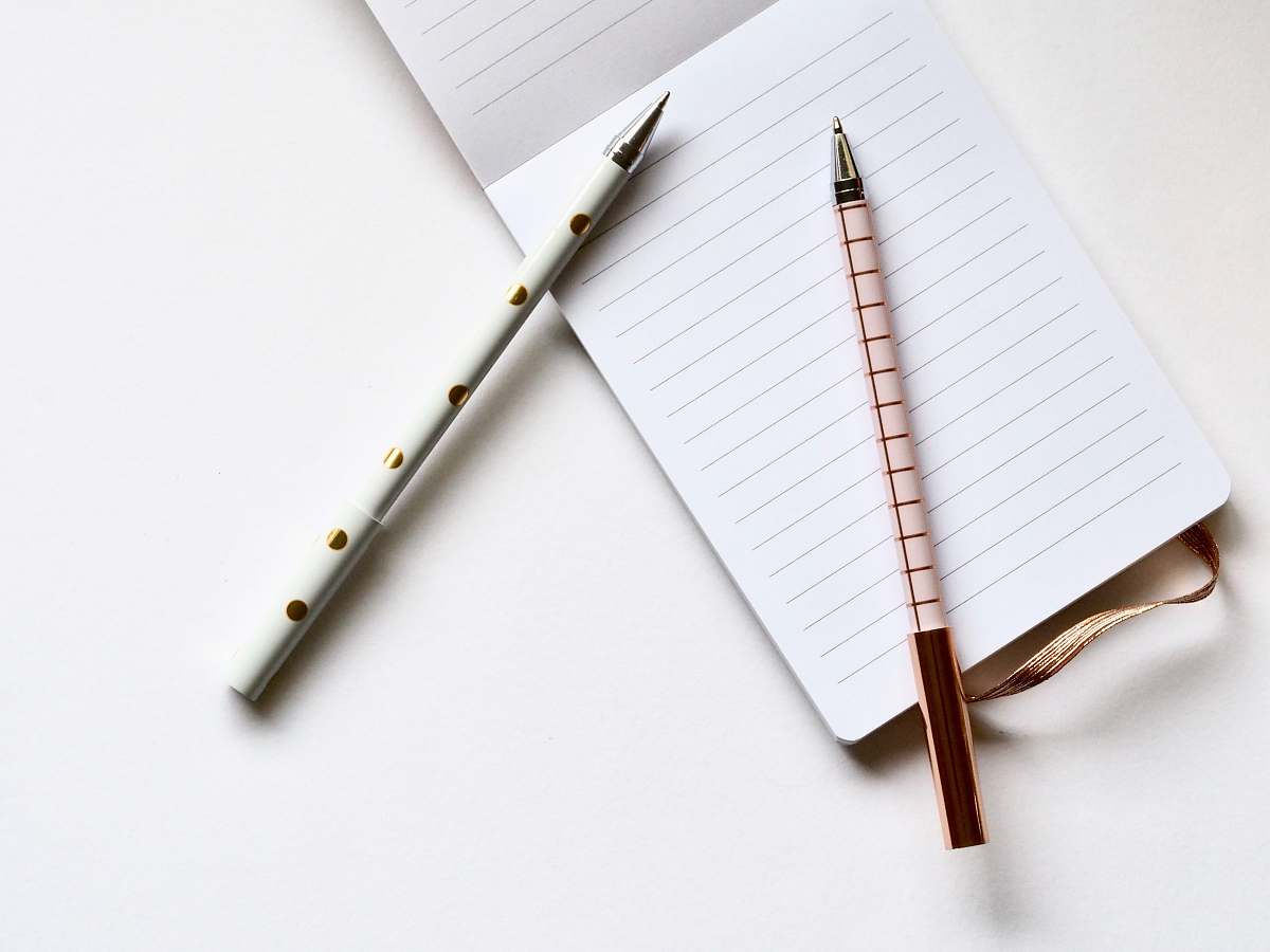 paper two white and beige pens on white paper notepad