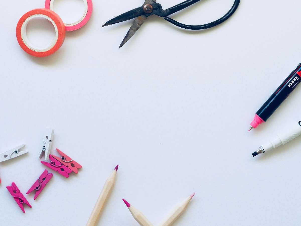 pencil black scissors near brown pencils on top of white textile background