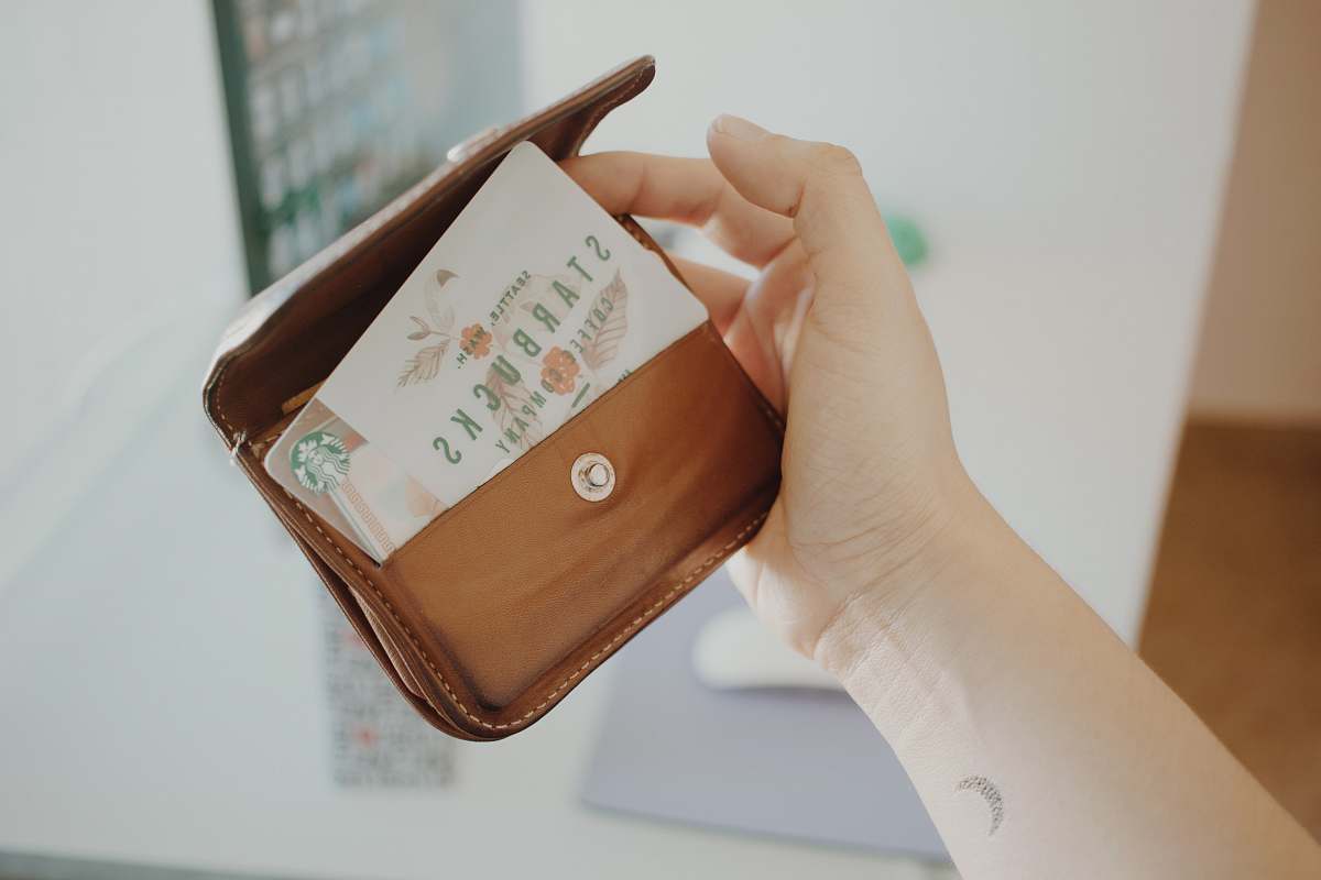card person holding brown leather coin purse hand
