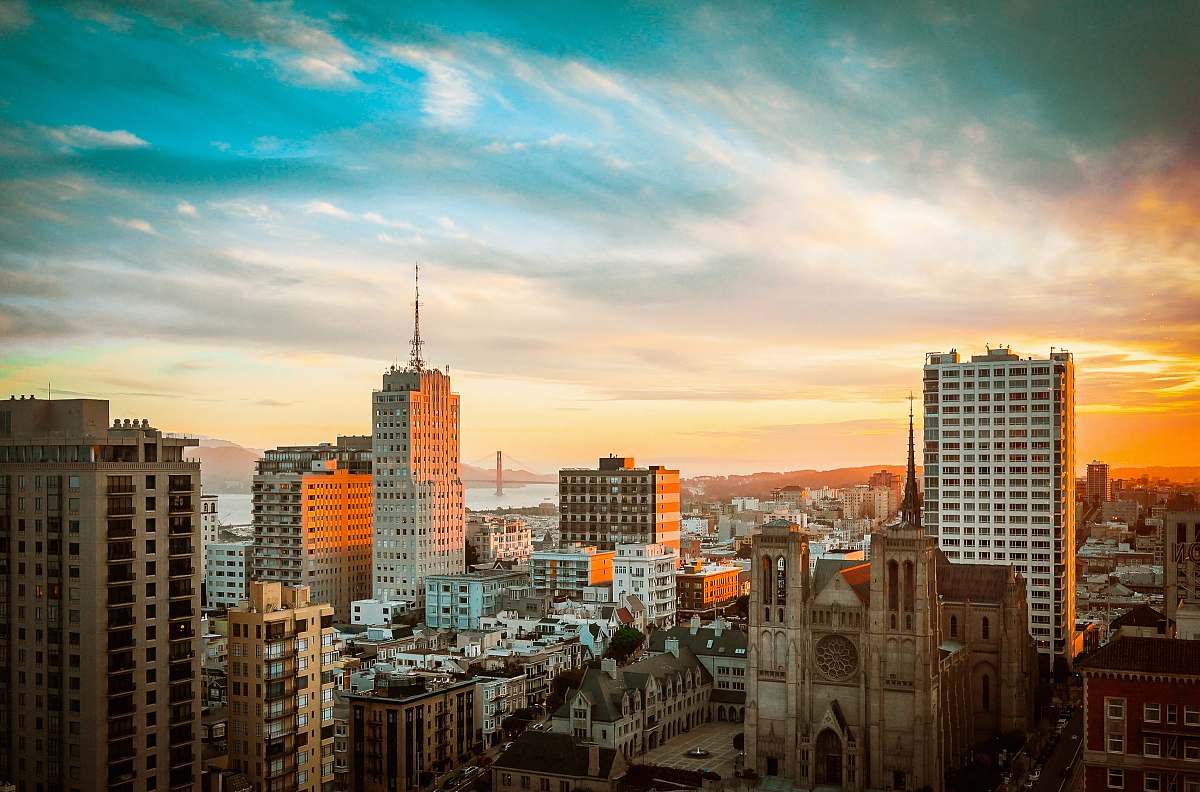 Capture the breathtaking beauty of a historic brown church nestled among modern buildings, as a vibrant sunset casts a warm glow over the urban landscape. This captivating scene is perfect for projects related to architecture, city life, or religious heritage. Ideal for use in travel brochures, inspirational articles, or promotional materials that highlight the charm of urban environments.