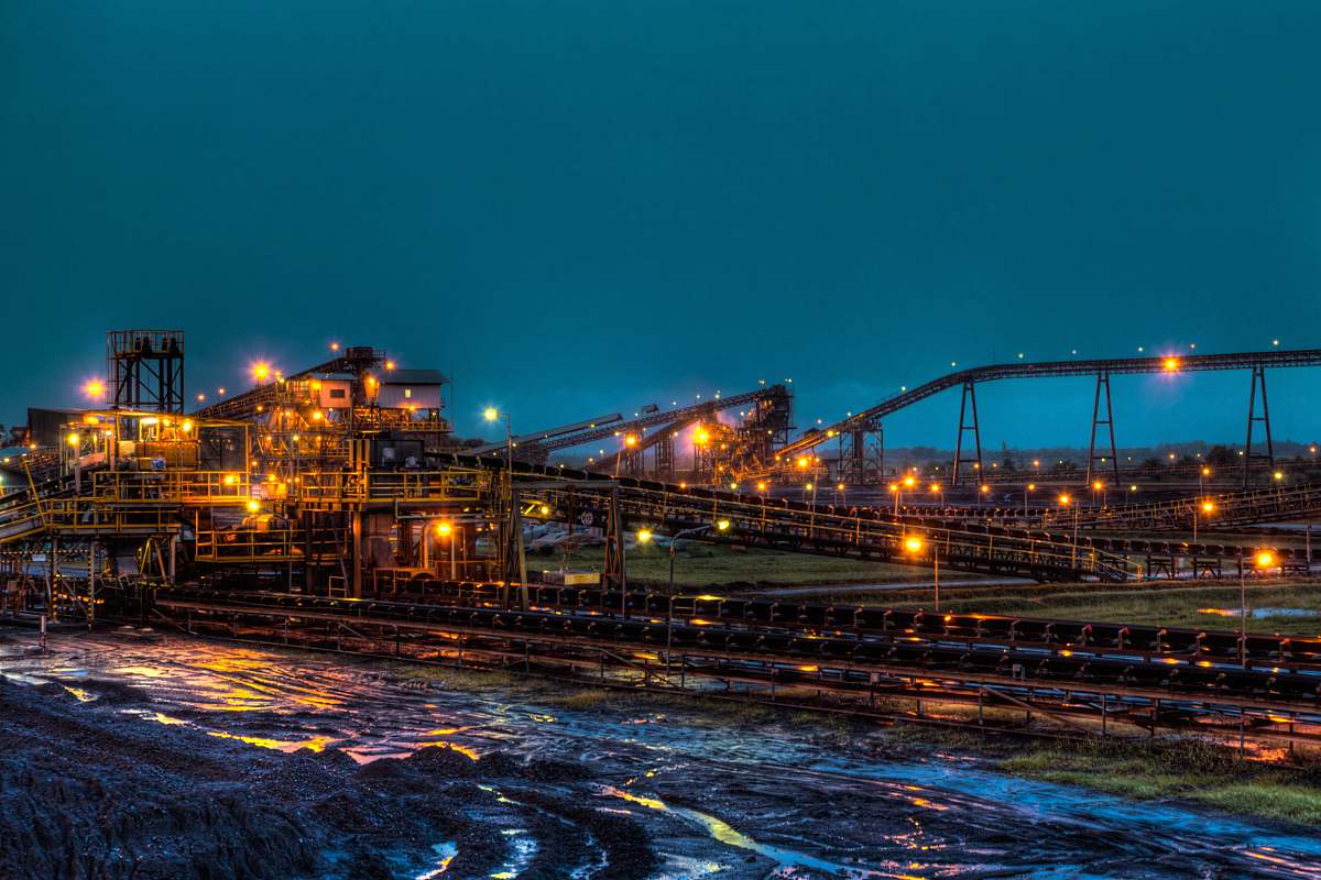 factory lighted brown concrete buildings near body of water at nighttime bridge