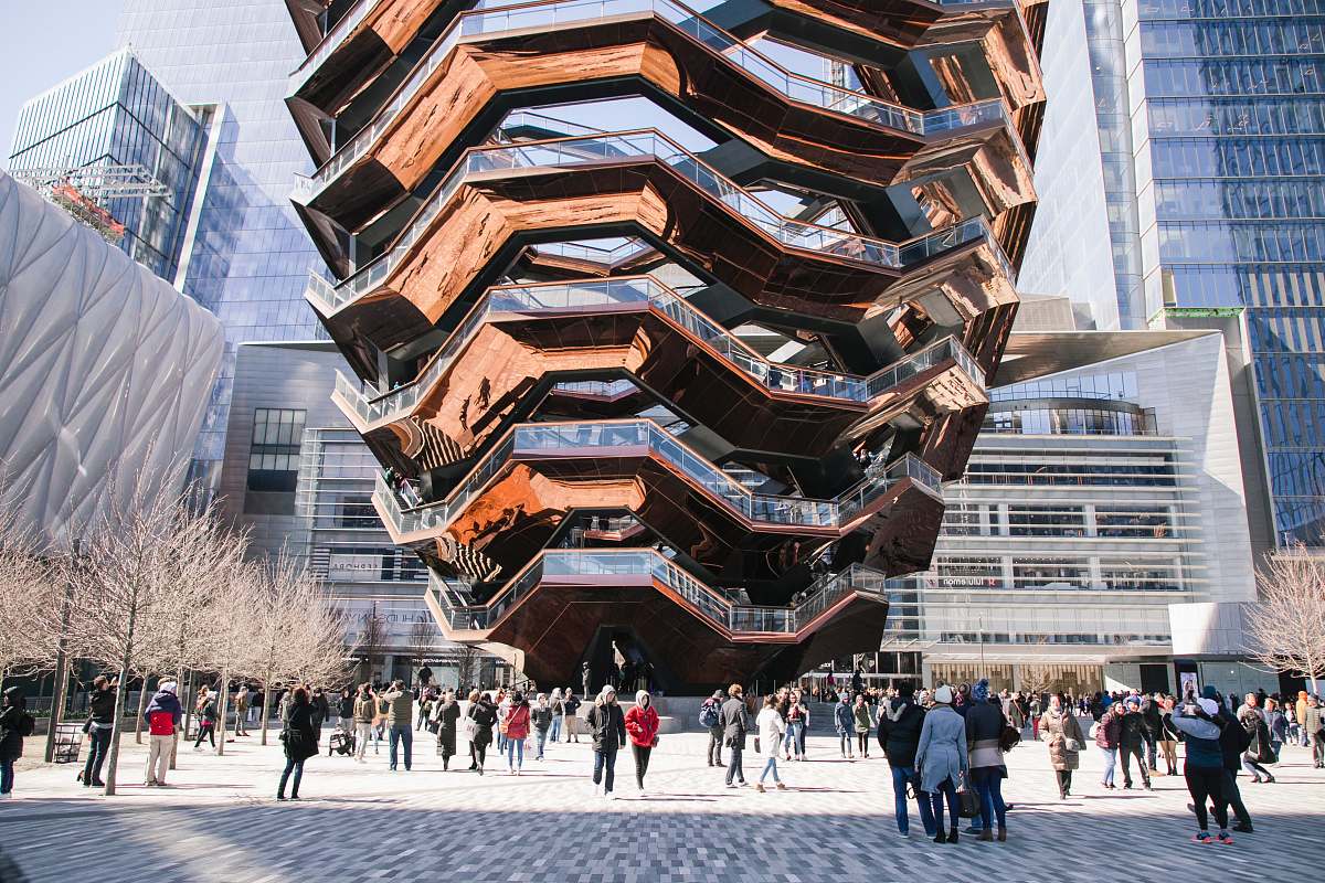city people on park below the giant sculpture person