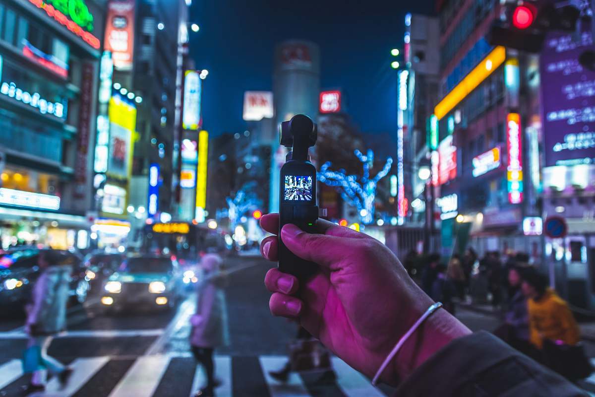 city person taking photo of people walking across pedestrian town