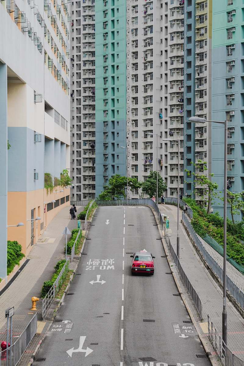 city red car travelling on road near buildings road