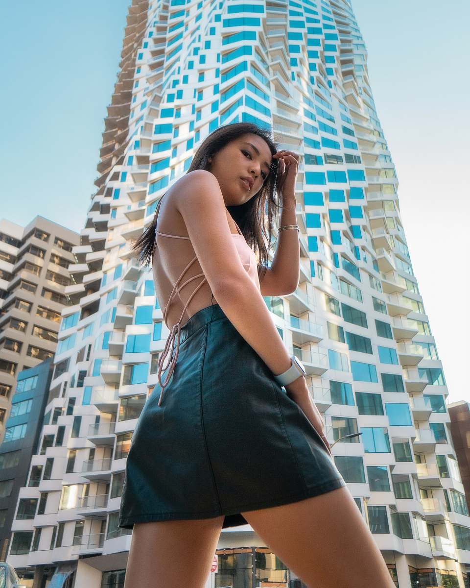 city woman wearing beige backless blouse and black leather miniskirt walking on street urban