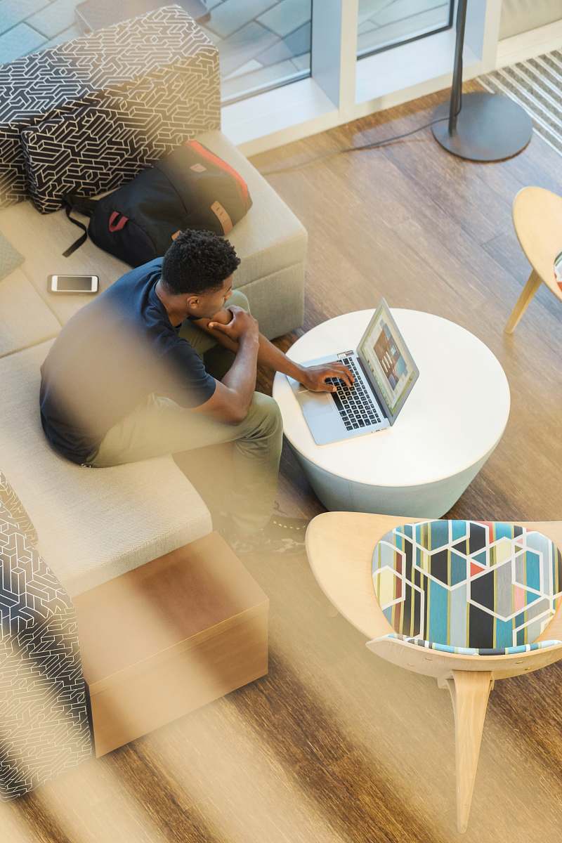 table man sitting on couch using MacBook furniture