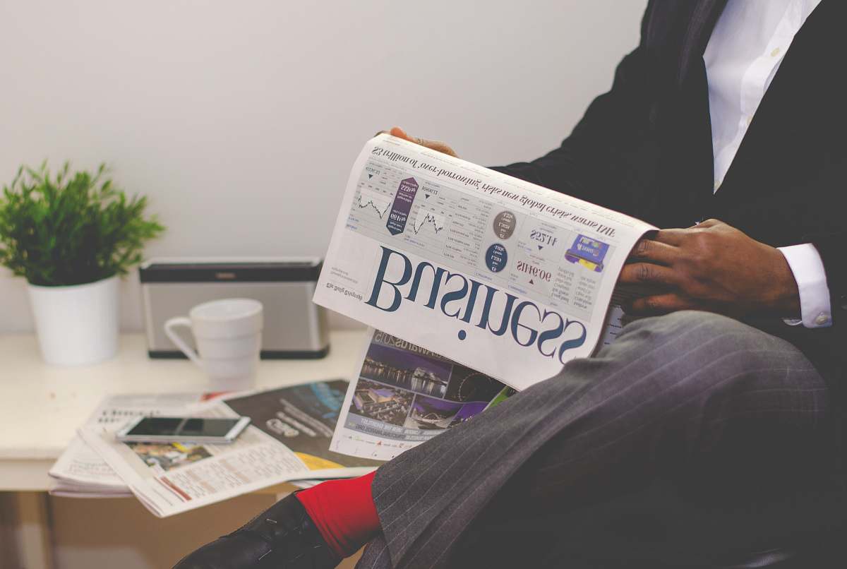 cup person sitting near table holding newspaper financial