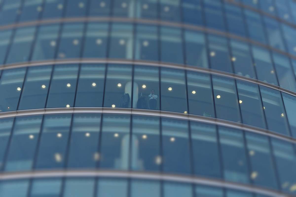 building selective focus photograph of person standing near building glass curtain grey