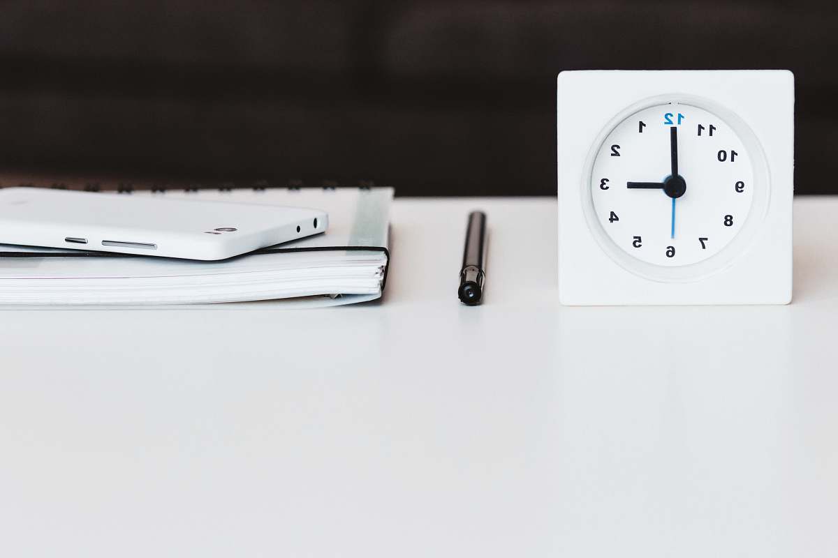 grey white desk clock near pen and book black-and-white
