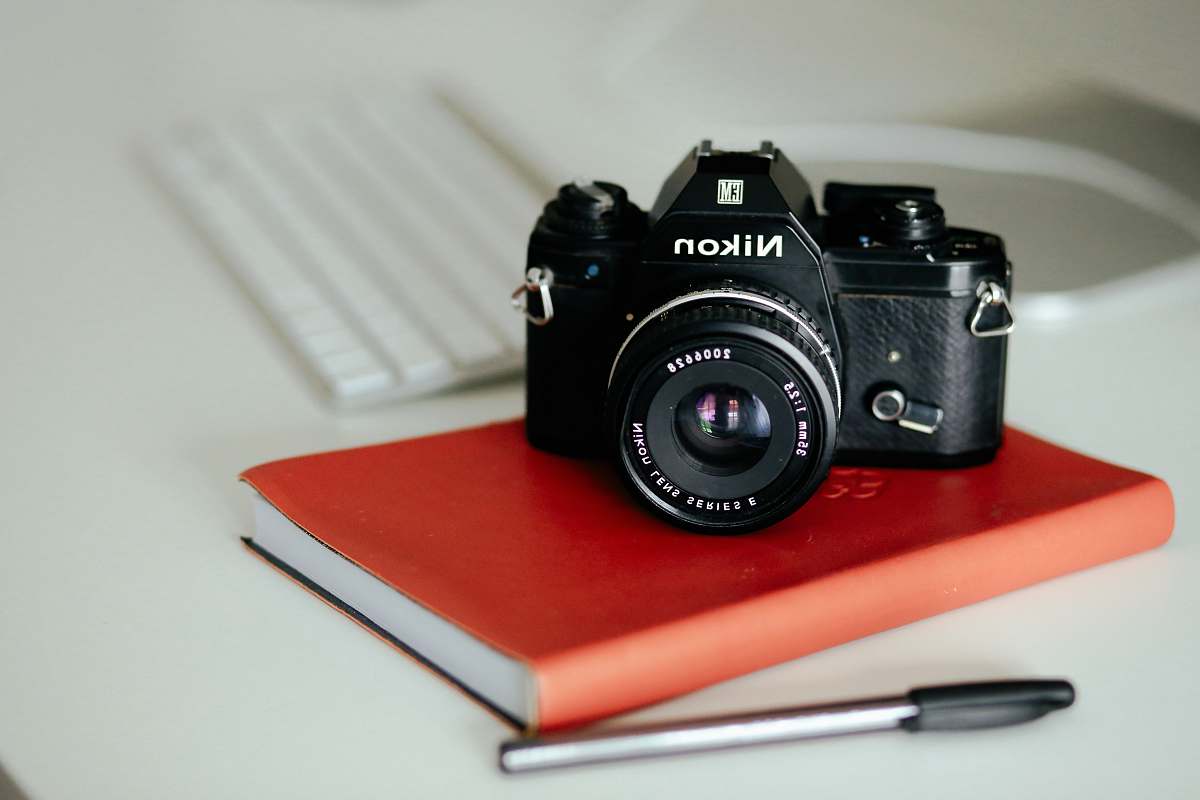 electronics black Nikon MILC camera on red book and pen nikon