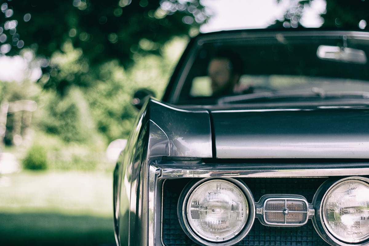 headlight man inside black muscle car automobile