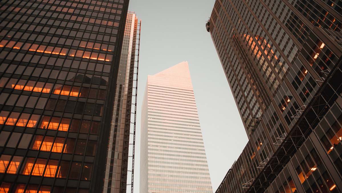 building low-angle photography of gray high-rise building between two curtain wall high-rise buildings during daytime urban