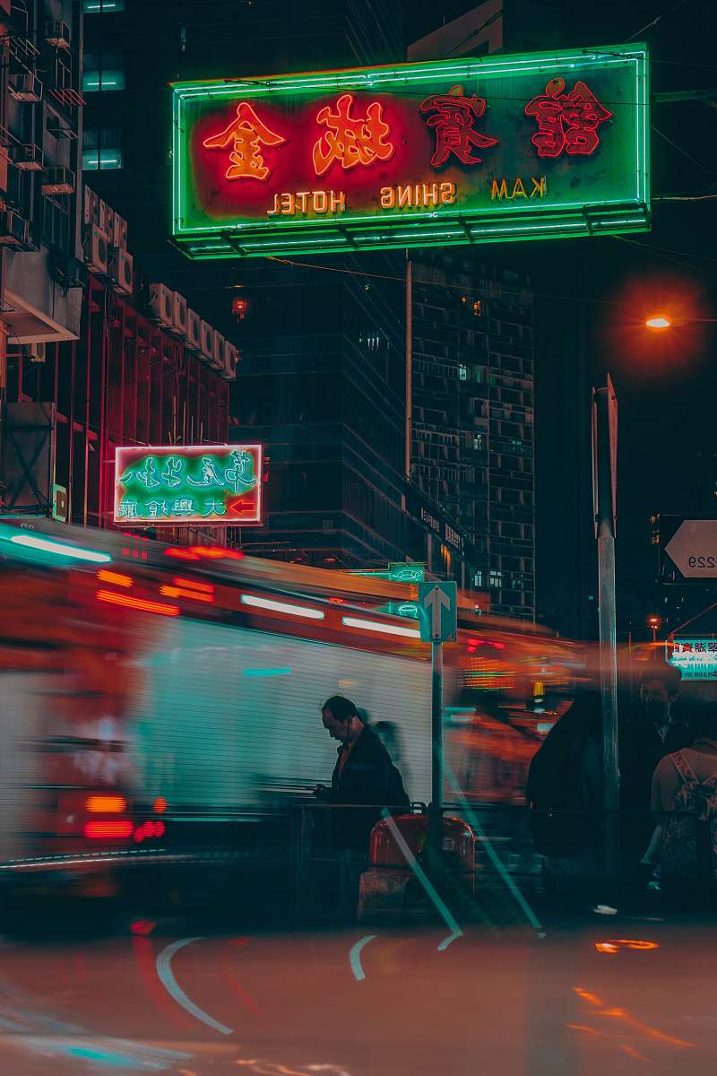 urban man wearing black jacket walking on street during nighttime metropolis