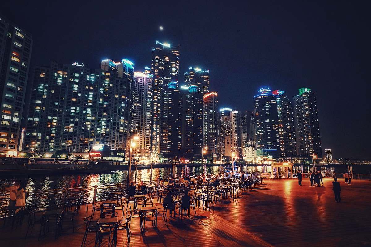 building people beside the river with buildings at the distance during nighttime town