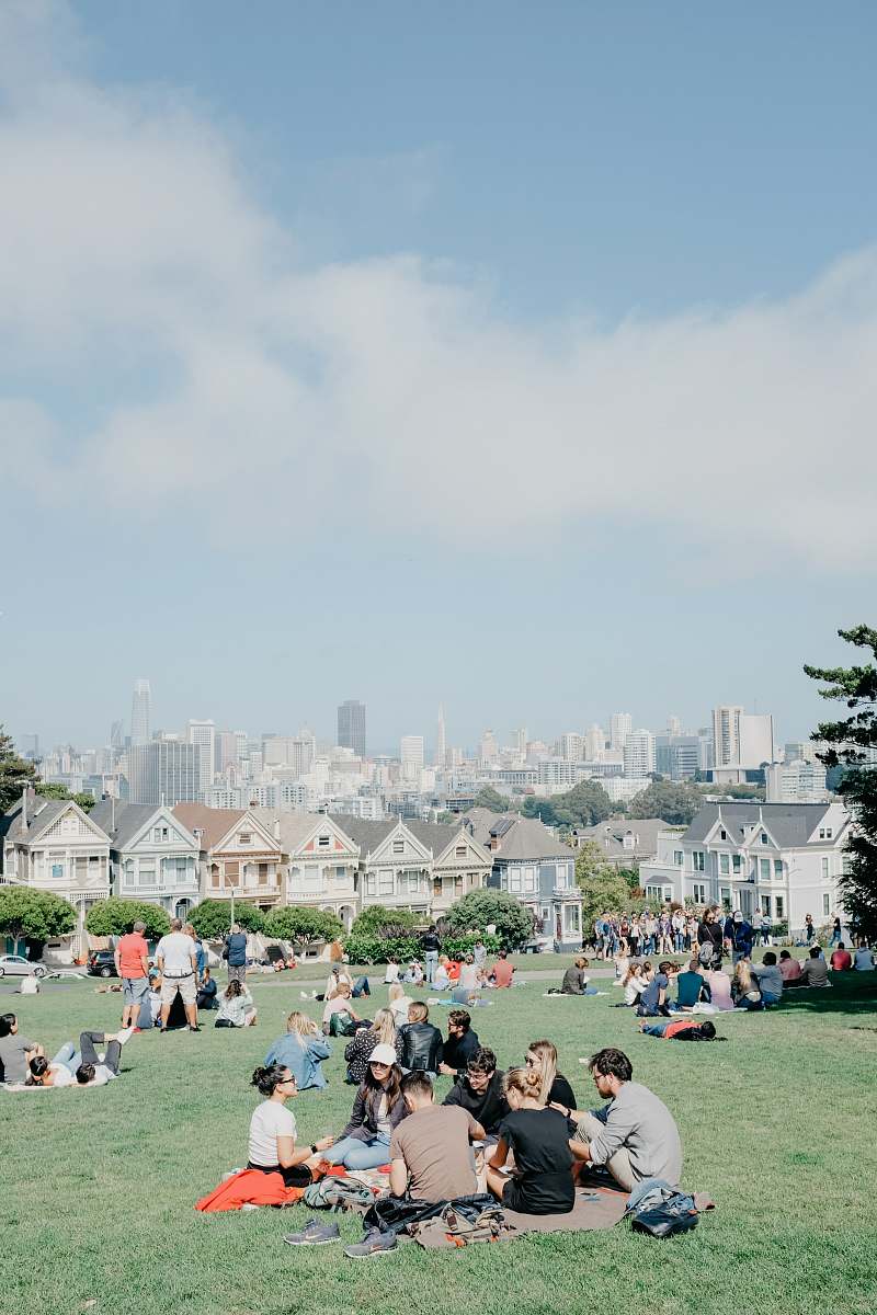 building people sitting on grass field during daytime downtown