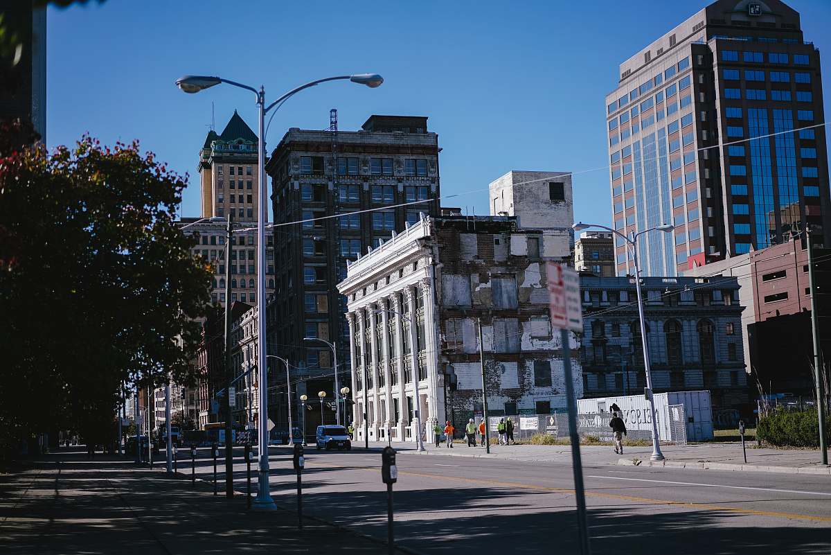 building vehicle passing on road beside white pillared building during daytime downtown