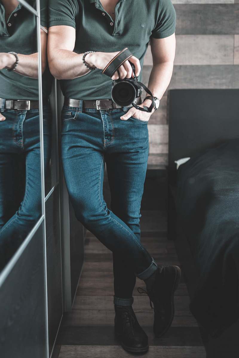 apparel man holding DSLR camera inside room pants