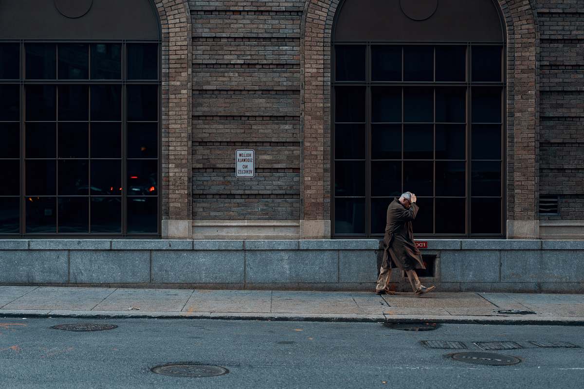 apparel person standing beside building during daytime human