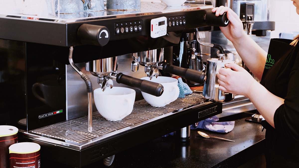 barista person holding black espresso maker machine