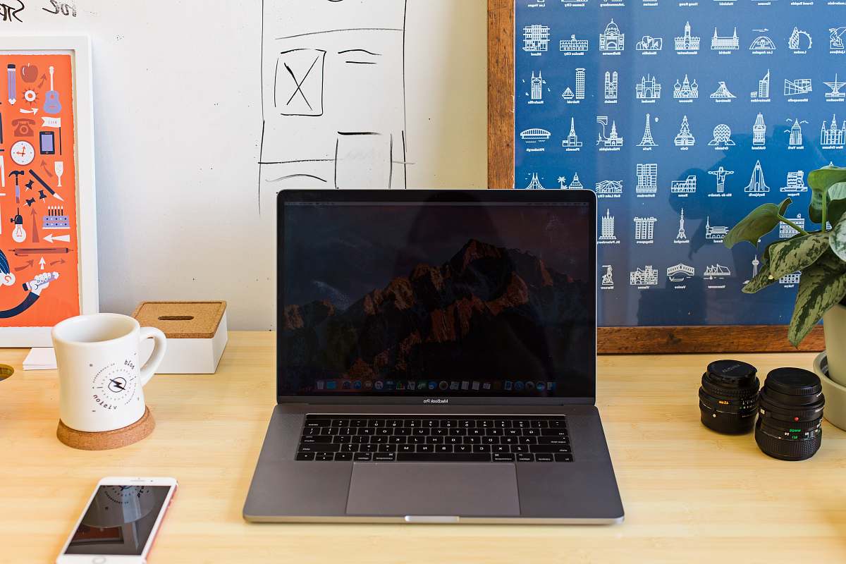 laptop Macbook Pro on table near white mug and PRODUCT RED iPhone desk
