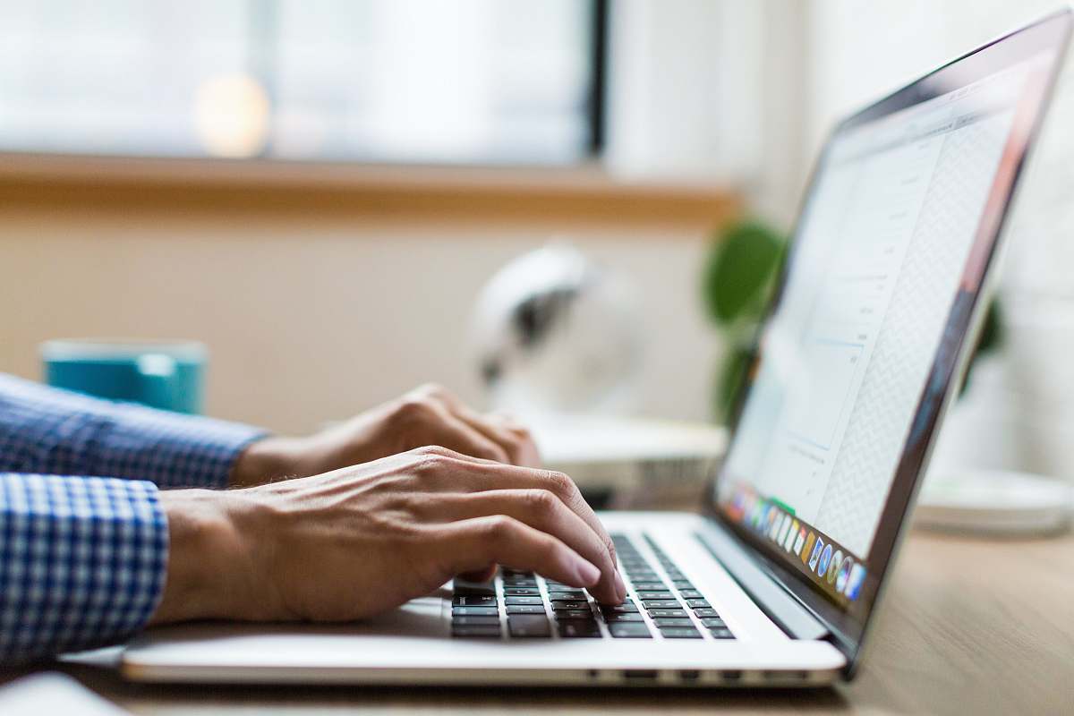 laptop person typing on silver MacBook paper