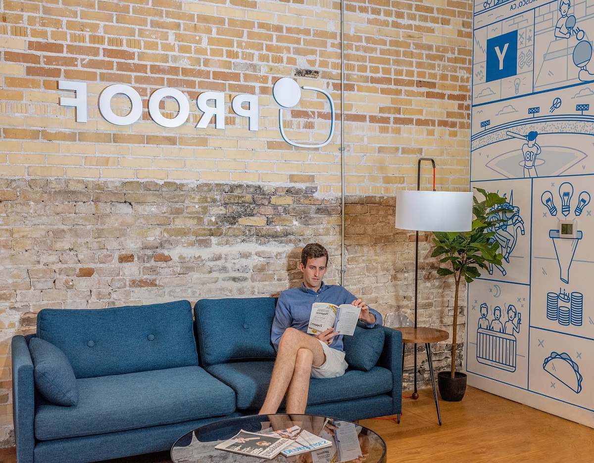 furniture man sitting on blue sofa while reading book indoors
