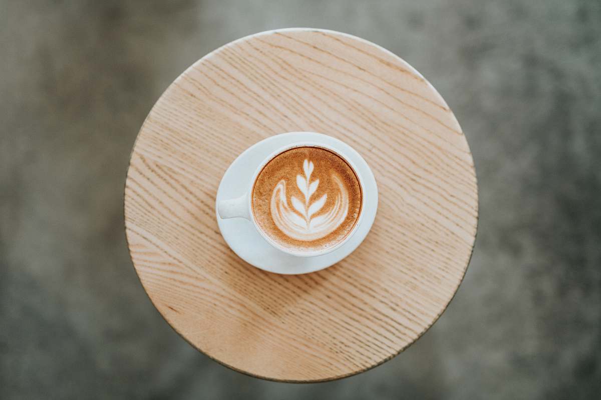 drink cappuccino on white ceramic mug with saucer on round brown coaster beverage