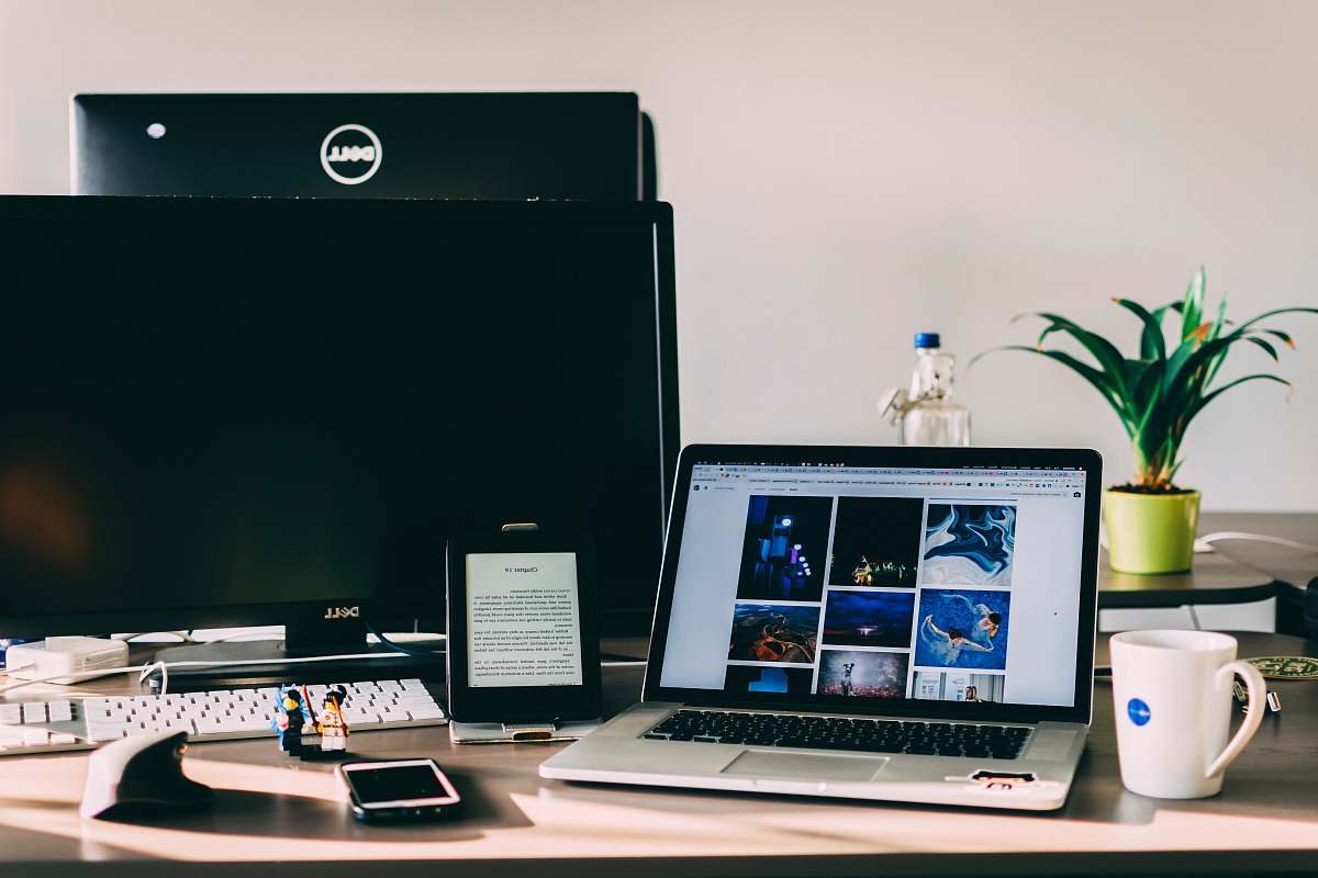 table black and gray laptop computer near flat screen monitor plant