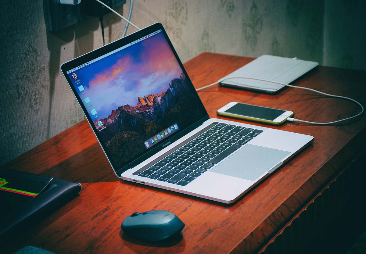 computer MacBook Pro on brown wooden surface laptop