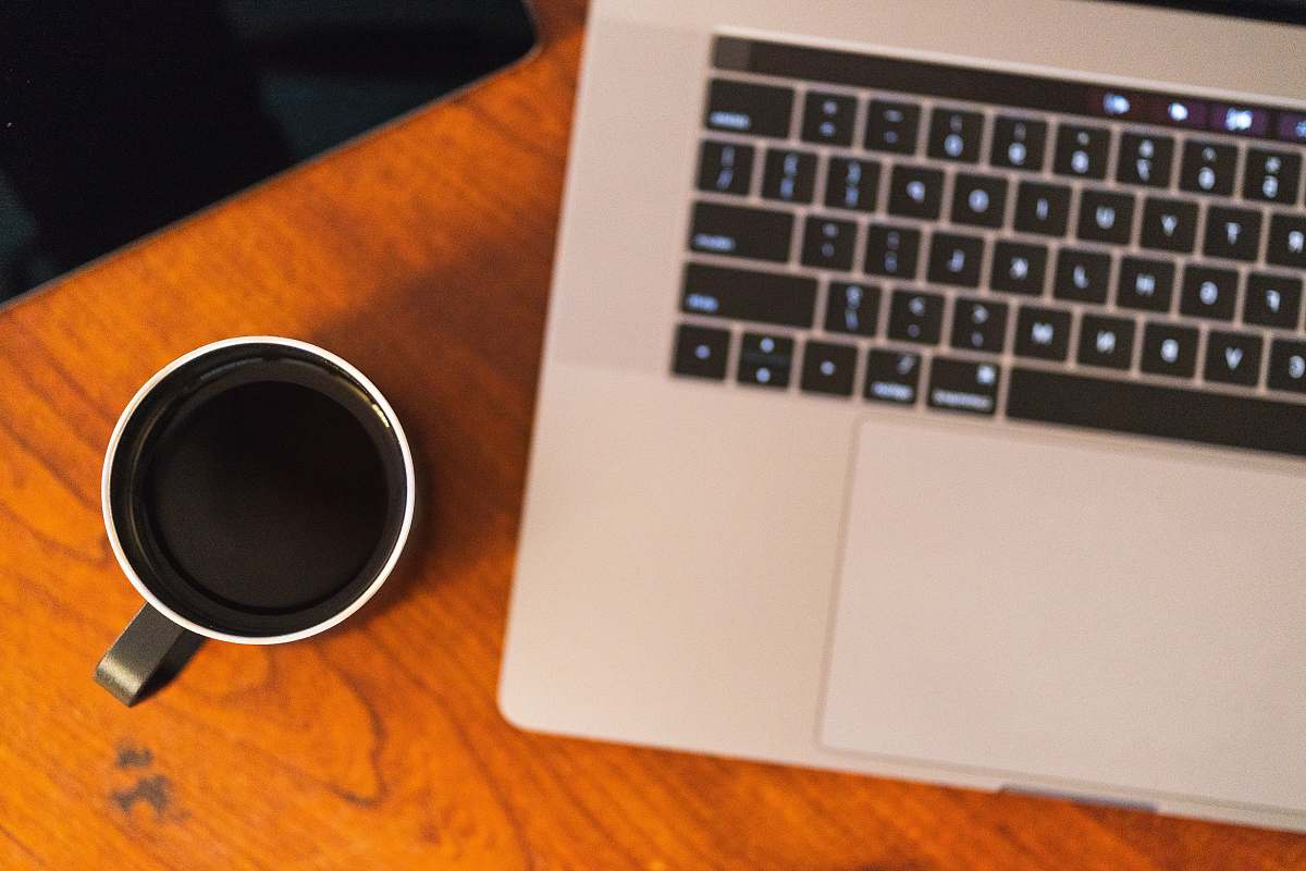 hardware black ceramic mug beside MacBook Pro on brown wooden surface computer hardware