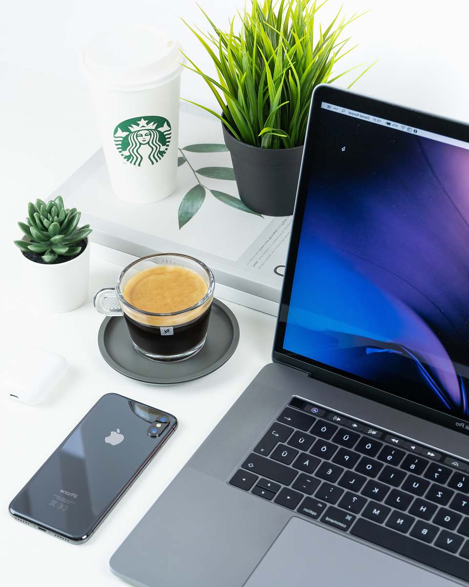 pc laptop beside iPhone and coffee in cup on table computer