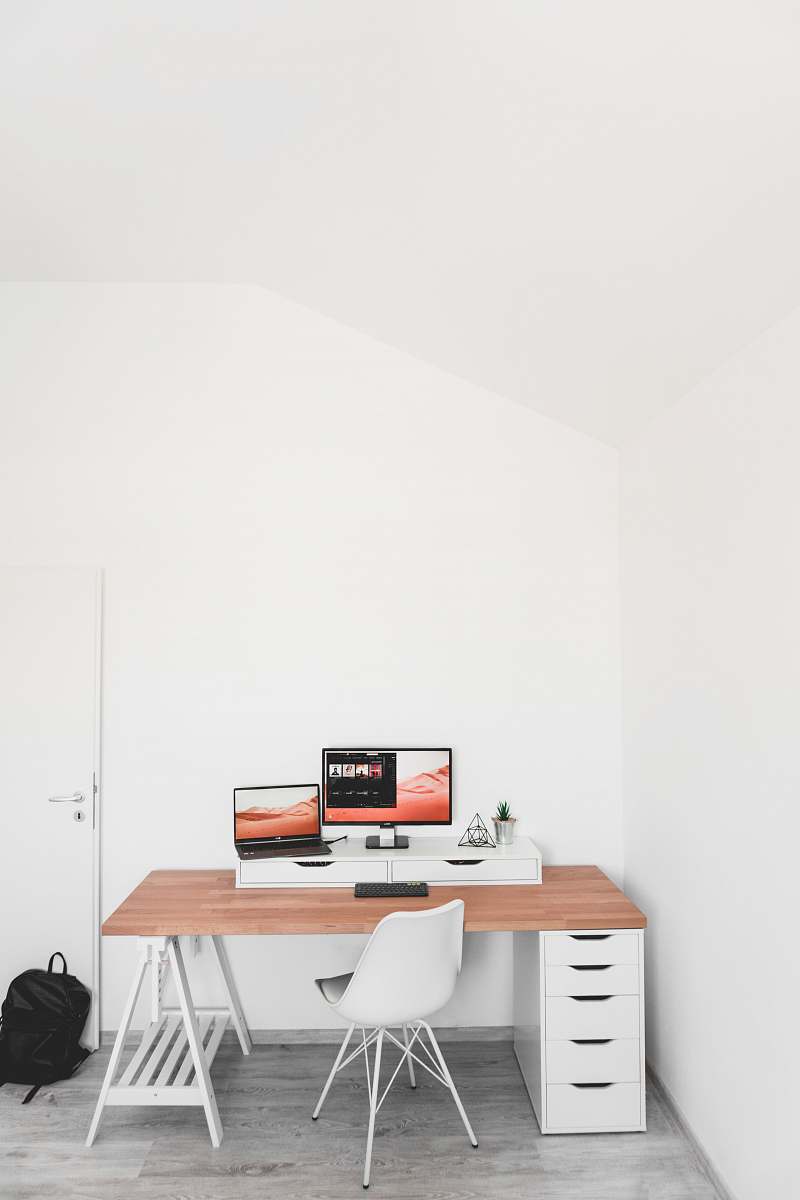 chair turned on flat screen monitor and laptop on desk table