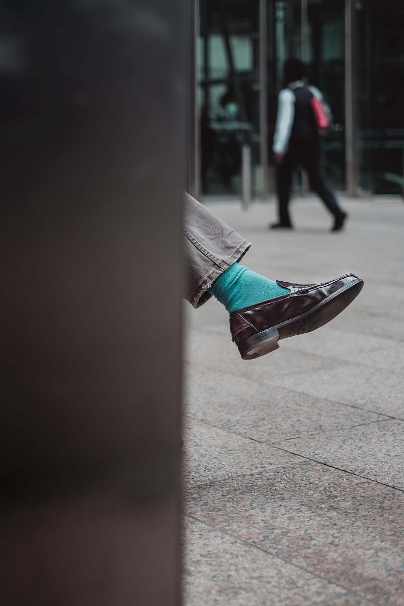 shoe person showing unpaired brown leather dress shoe street