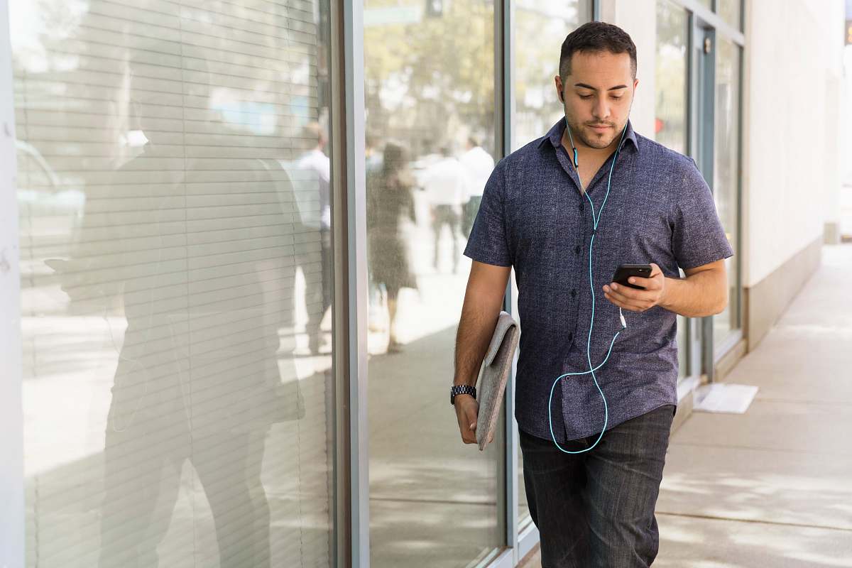person man in blue button-down shirt walking beside glass wall during dayhtime people