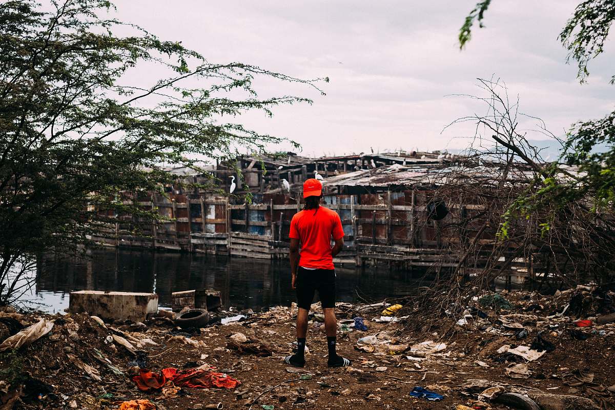 person man in red shirt facing house building