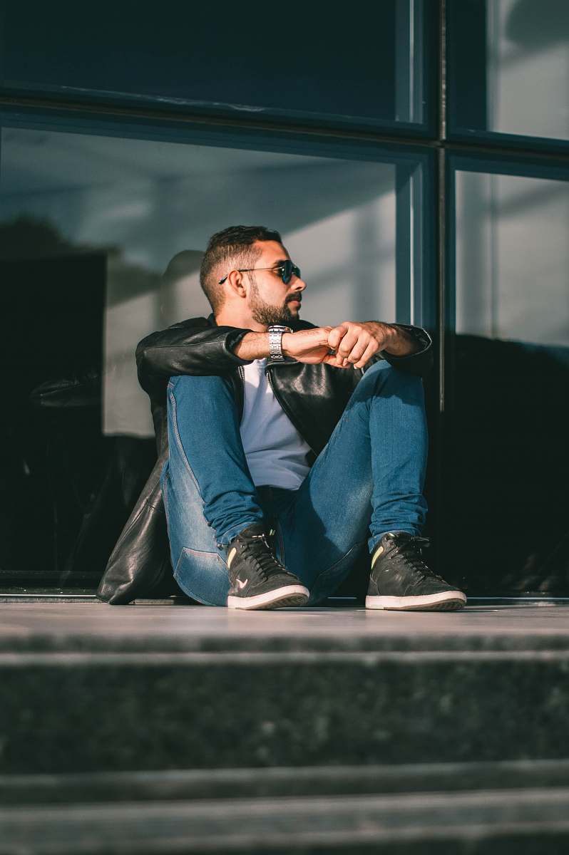 person man sitting on floor leaning on glass wall inside room people