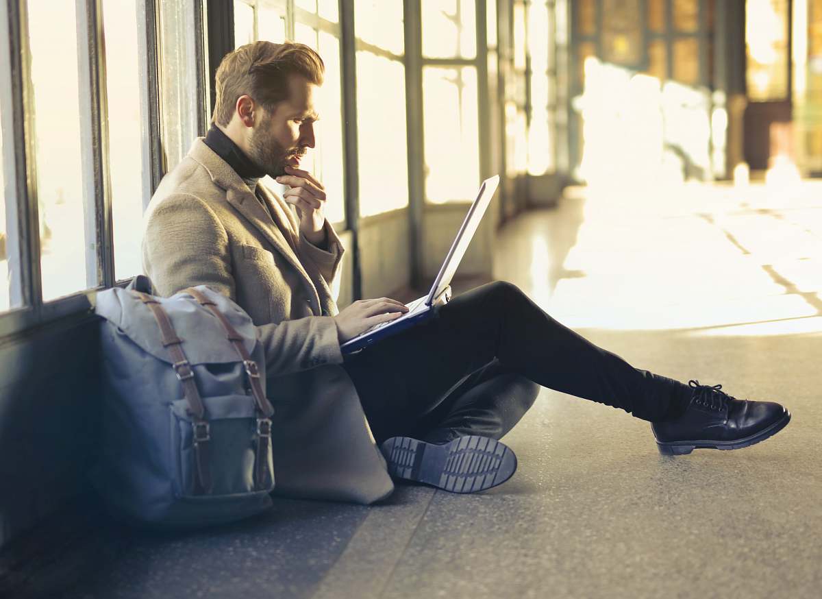 people man sitting on floor while using laptop person