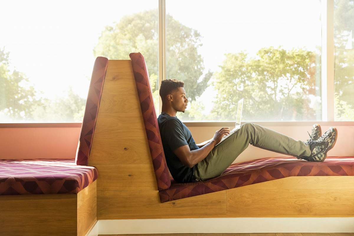 person man sitting on red cushion beside window people