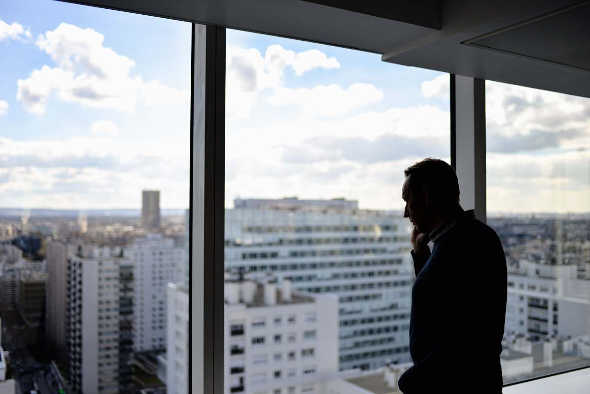 person man standing beside glass window paris